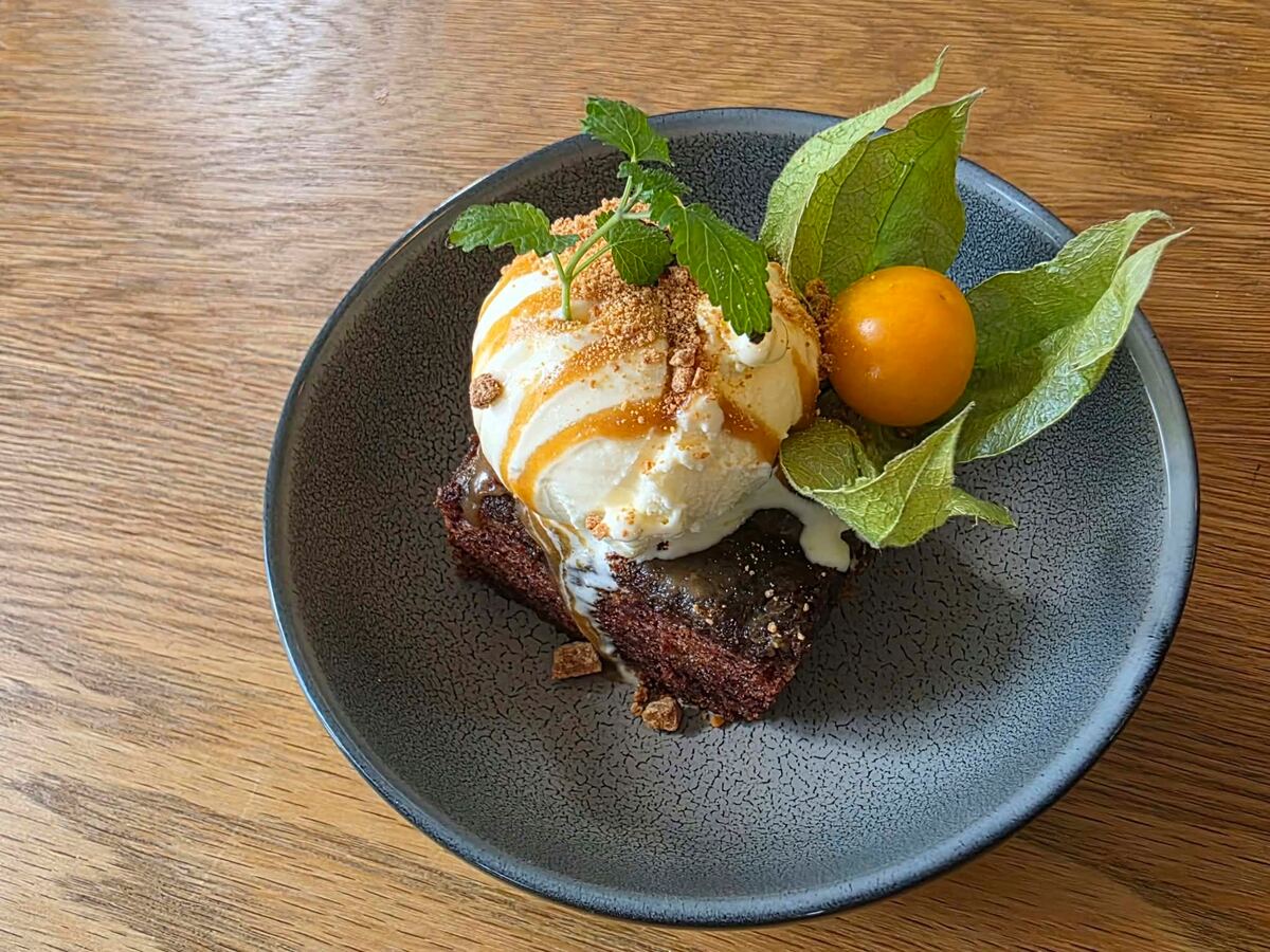Sticky toffee pudding med vaniljeis, karamellsaus, smuler, mynte og en fysalis
