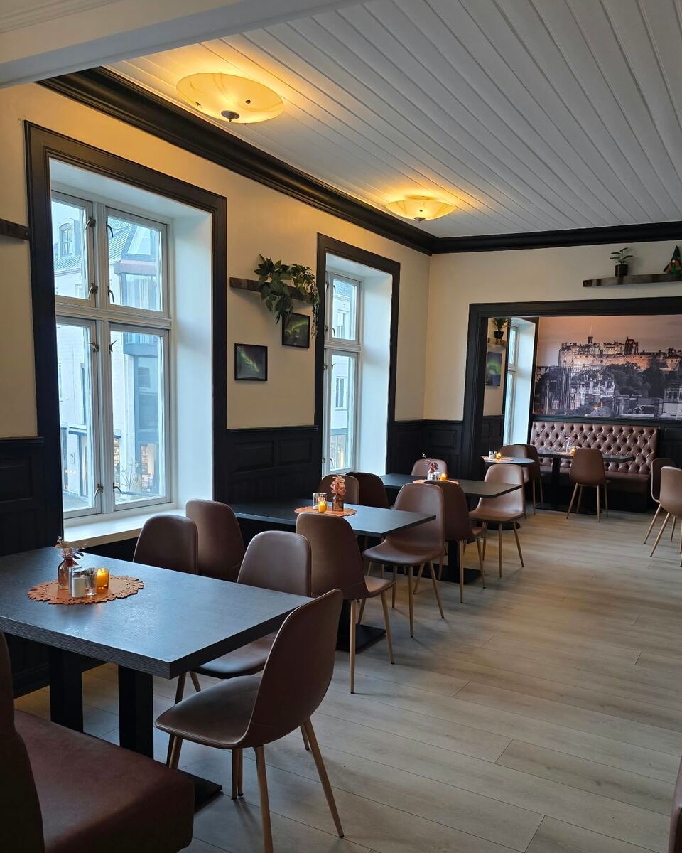 Lyst rom i 2. etasje med høye vinduer mot gata og utsikt inn til rommet med skinnbenkene